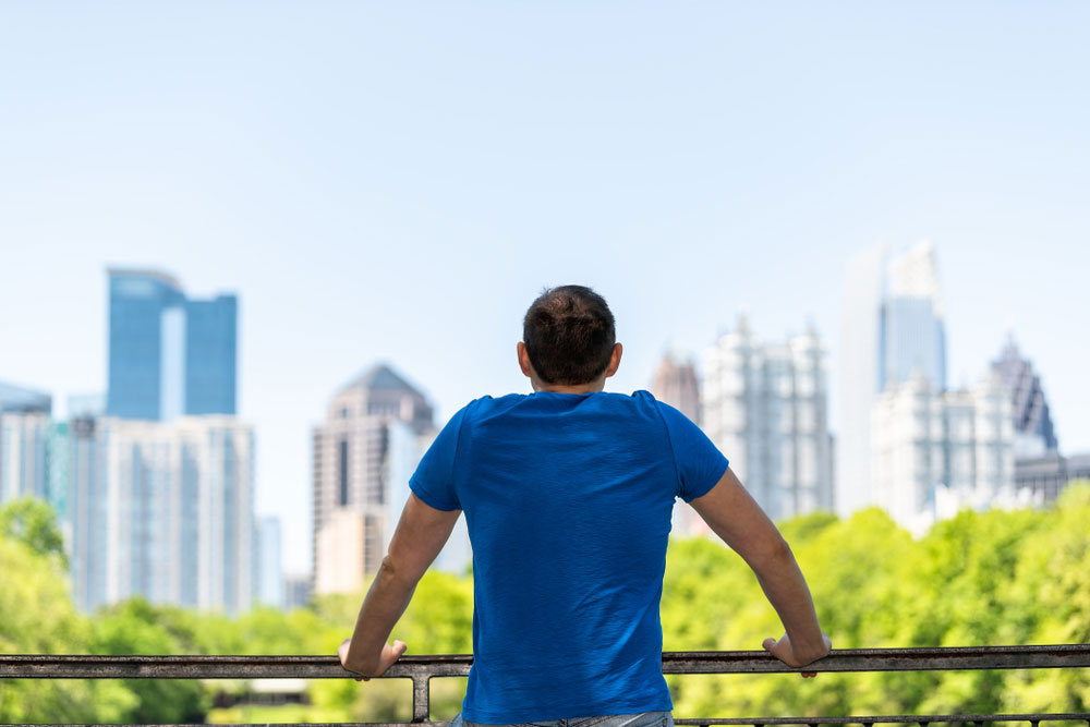 man in blue shirt looking at Atlanta skyline from railing