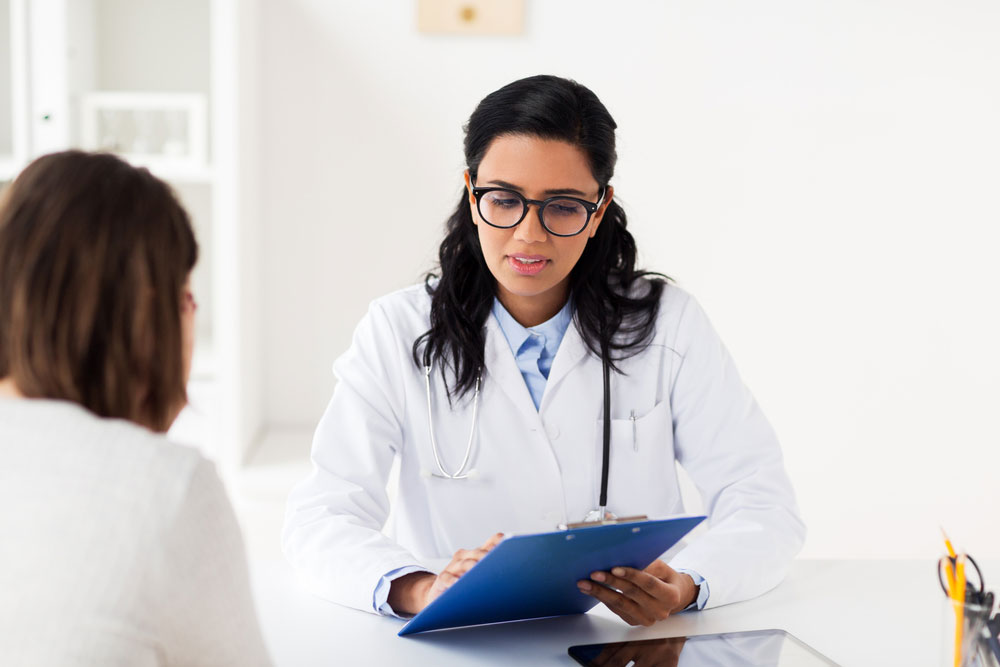 female doctor with glasses looking at clipboard with patient