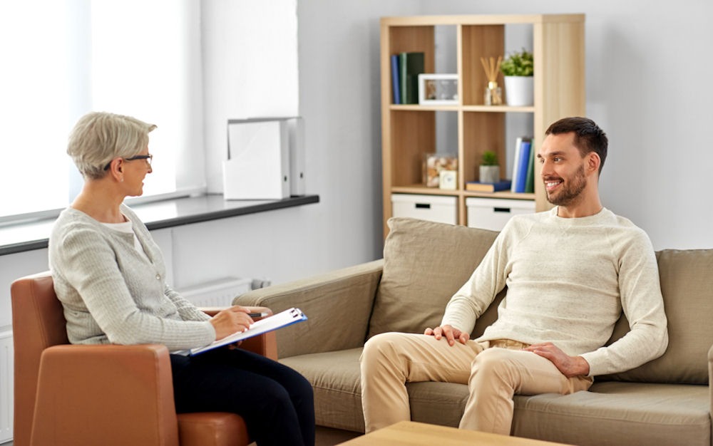 a man talking to his therapist while he is smiling